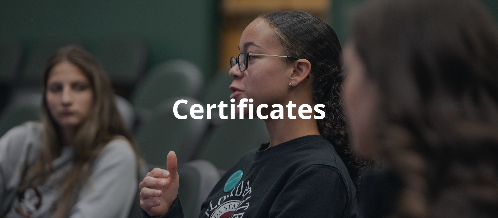 "A woman wearing glasses talking to a classroom of students with the word Certificates overlaid."
