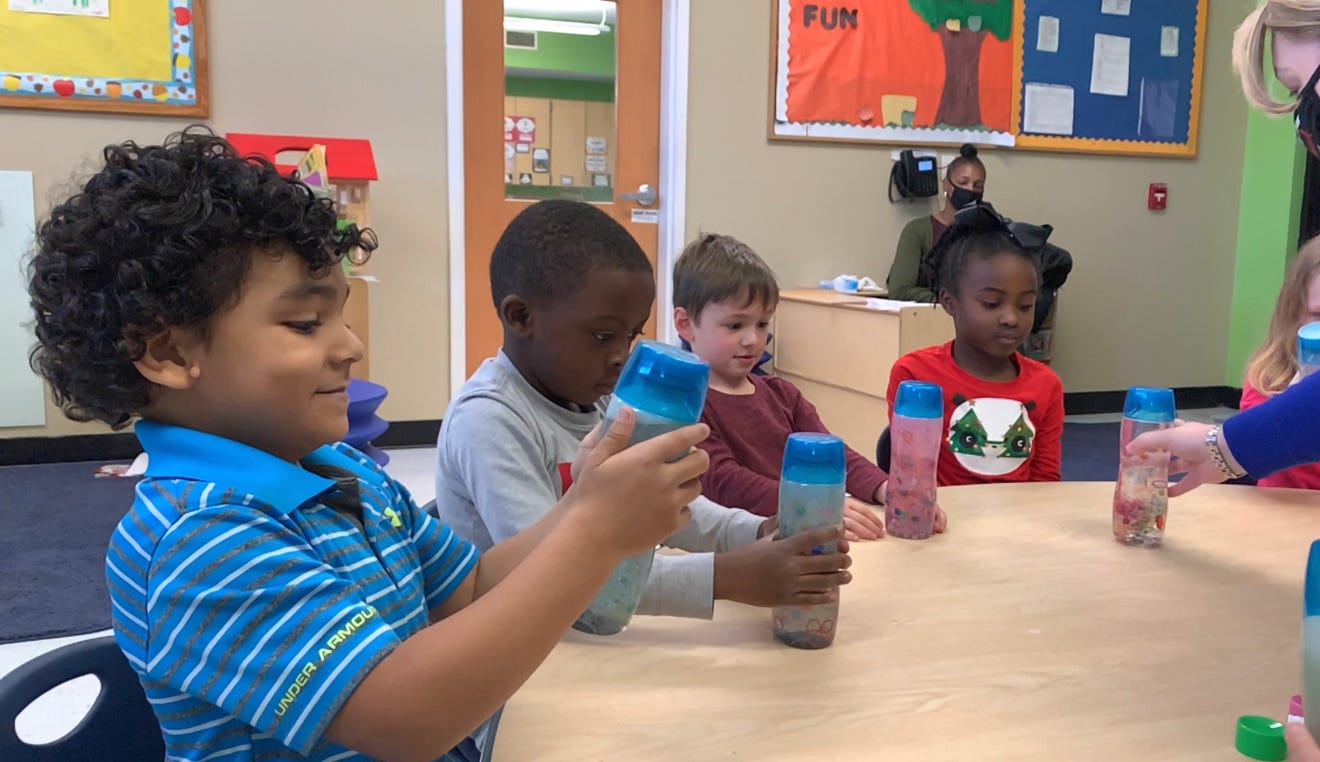 "Young children playing at a table in a colorful classroom."