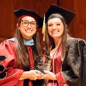 "Dr. Lyndi Bradley posing with Gabrielle Brandon winner of the Institute for Trauma and Resilience Studies Director's award posing in graduation regalia."