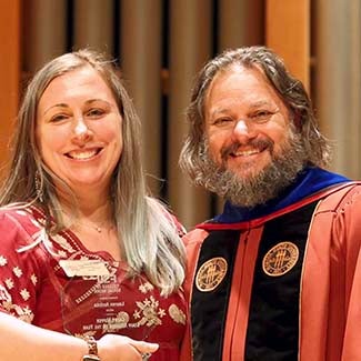 "2026 Staff Member of the Year Lauren Antista holder her octagonal crystal award posing with Dean David Springer."