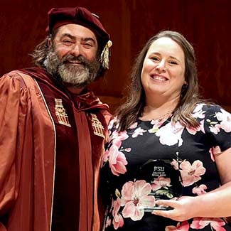 "Dr. Stephen Tripodi posing with Doctoral Student of the Year Lauren Herod holder her octagonal crystal award."