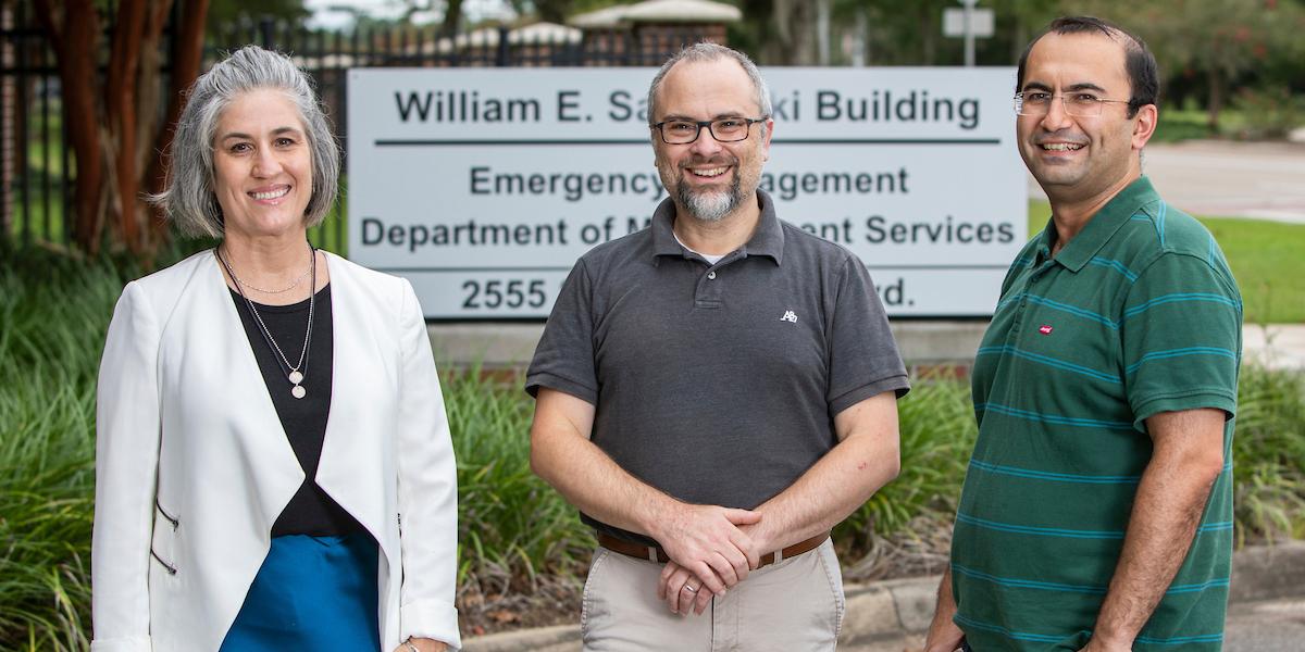 "Ellen Piekalkiewicz, Dr. Arda Vanli and Dr. Eren&nbsp;Erman Ozguyven posing in front of the Emergency Management, Department of Management Services.&nbsp;&nbsp;"