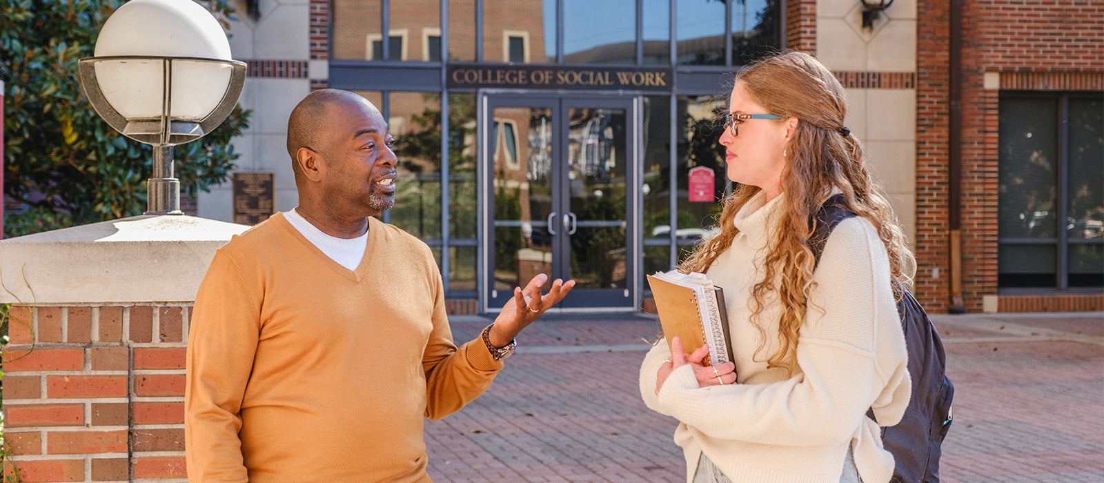 "Faculty member Keithen Mathis talking to a student in the University Center C courtyard"