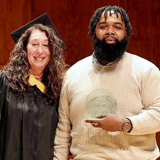 "MSW Director Fran Gomory posing with MSW Student of the Year Davonte Fason holding his octagonal crystal award."
