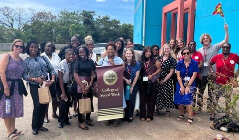 Social work students posing with an FSU College of Social Work banner outside in Grenada, West Indies.