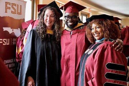 Graduate student posing with faculty members Fran Gomory and Dr. Carol Edwards all dressed in regalia at the 2026 Spring Graduation Event.