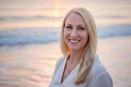 Alumna Sunshine Arnold posing in front of a Florida beach with the ocean in the background.
