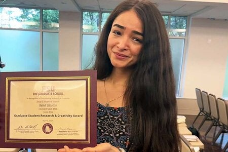 Doctoral student Beren Crim Sabuncu holding her paper certificate for her 2026 Florida State University Doctoral Student Research and Creativity Award.