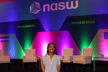 Jalynn French posing in front of a colorful lit display at the National Association of Social Workers National Conference.