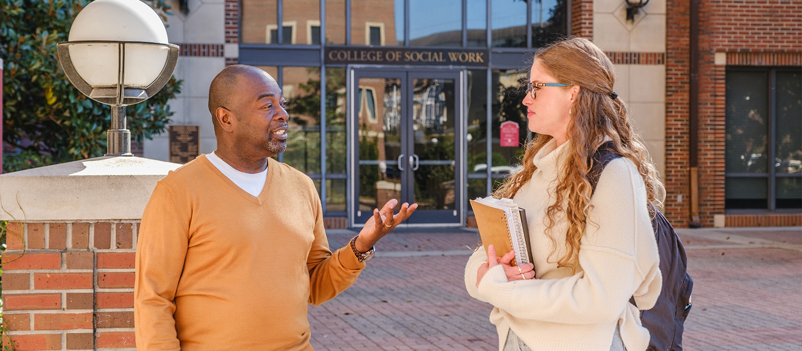 "Faculty member Keithen Mathis talking to a student in the University Center C courtyard"