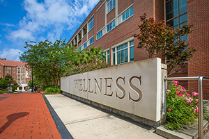 "Photo of the outside of the University Health Services Building and a closeup of a cement sign that says Wellness""