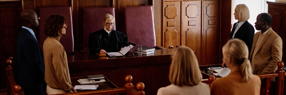 "A judge at the bench in a courtroom surrounded by people"