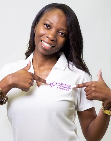 Kyra Adams wearing a white shirt and she is pointing to its logo that says Maternal and Perinatal Services