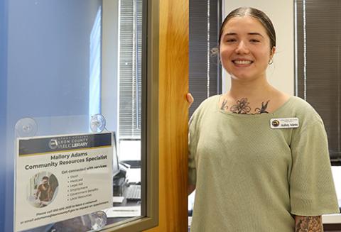 Mallory Adams standing at her office door with her name plate on the door.