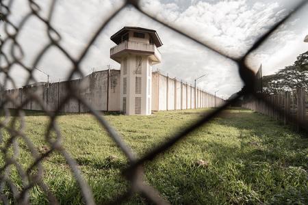 Photo of Prison Guard Tower through a chain link fence.