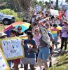 Photo by Lara Klopp of a Pride rally including people with signs and wearing rainbow and LGBTQ Pride clothing.