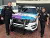 FSU Police Department Interim Chief Justin Maloy and FSU Police Officer Dinorah Lawson standing with a police care wrapped in a Domestic Violence Awareness Month graphic at Cascades Park 