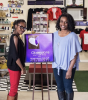 Nijah and Betty pose with a sign that reads Obsessions Gift Shop in the entrance of their store